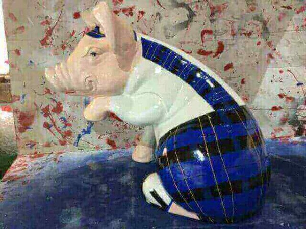 Sitzendes Schwein im blauen Schottenrock